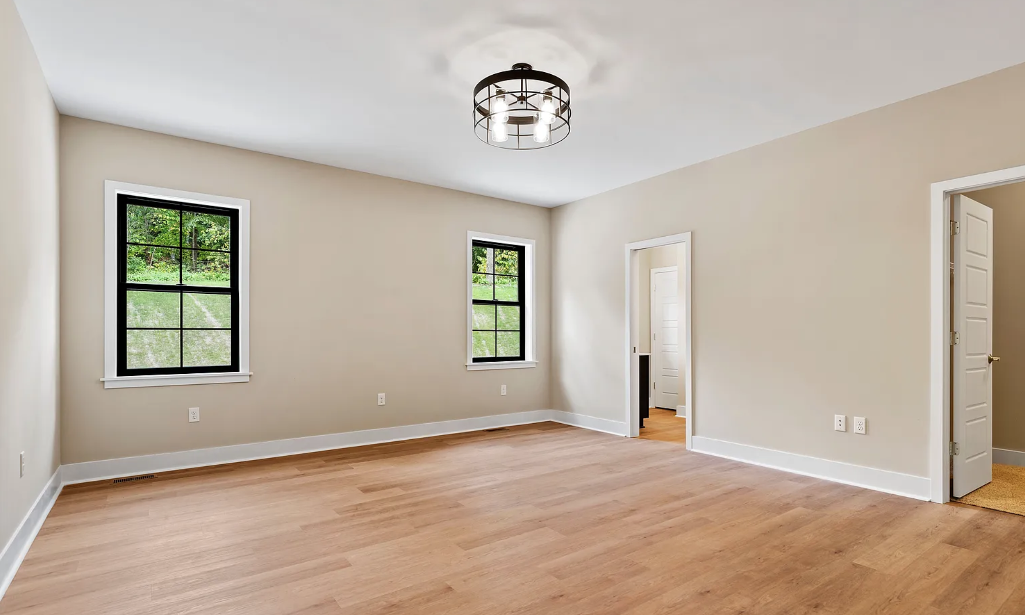 Empty bedroom with natural lighting, hardwood floors, and large windows in a Rockville Estates home by Yingst Building Group