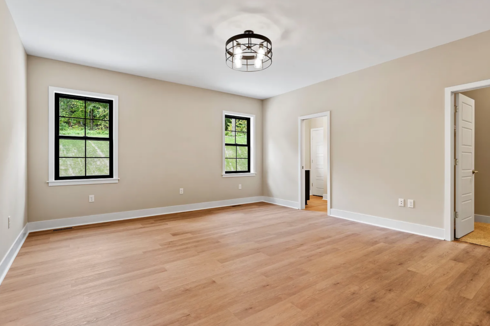 Empty bedroom with natural lighting, hardwood floors, and large windows in a Rockville Estates home by Yingst Building Group